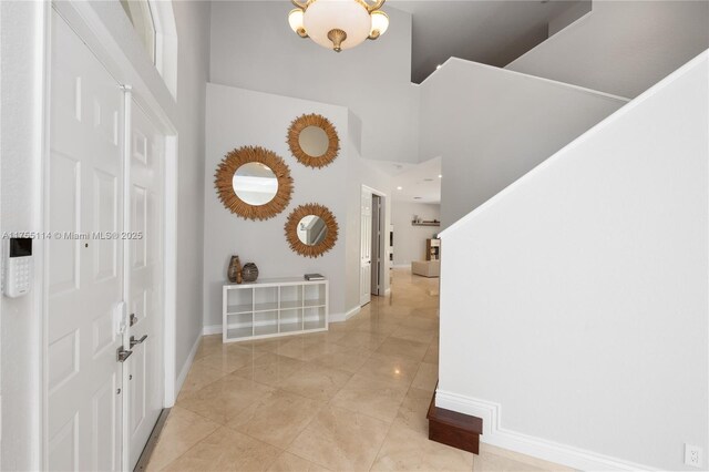 hallway with baseboards and a towering ceiling