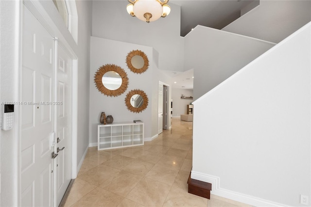 foyer entrance with baseboards, a high ceiling, and light tile patterned flooring