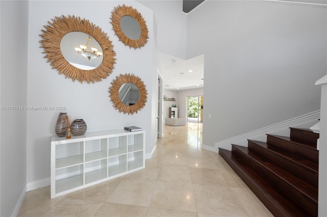 hall with baseboards, a chandelier, and stairway