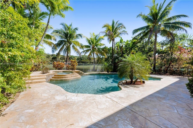 view of swimming pool featuring a patio, fence, and a pool with connected hot tub