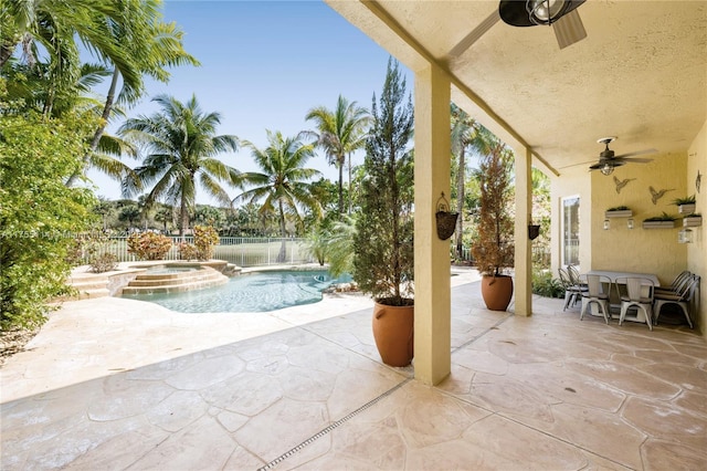 view of patio featuring fence, a ceiling fan, and a pool with connected hot tub