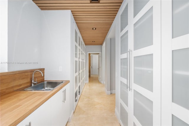 corridor featuring a sink, wood ceiling, and light tile patterned floors