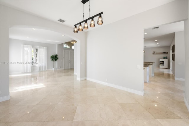 empty room featuring baseboards, arched walkways, visible vents, and recessed lighting
