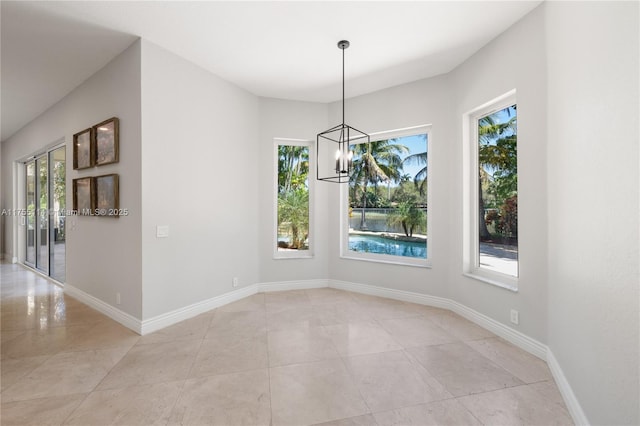 unfurnished dining area featuring light tile patterned flooring, a healthy amount of sunlight, and an inviting chandelier
