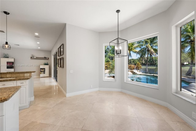 unfurnished dining area featuring recessed lighting, light tile patterned flooring, a sink, and an inviting chandelier