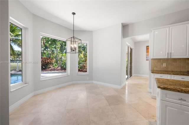 unfurnished dining area featuring light tile patterned floors, an inviting chandelier, and baseboards