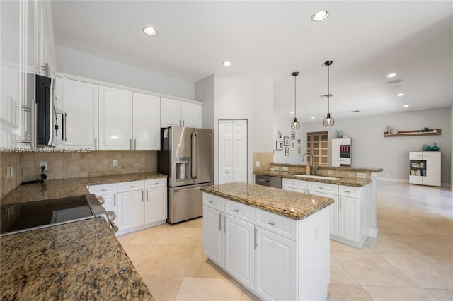 kitchen with stainless steel appliances, a peninsula, a sink, tasteful backsplash, and white cabinetry