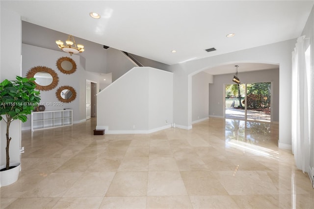 unfurnished living room featuring arched walkways, recessed lighting, and an inviting chandelier