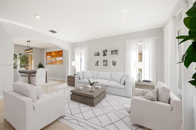 living room featuring arched walkways, baseboards, visible vents, recessed lighting, and light tile patterned floors