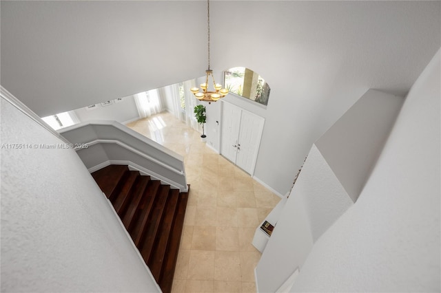 stairs featuring tile patterned flooring, a towering ceiling, and an inviting chandelier