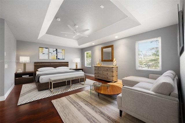 bedroom featuring baseboards, a raised ceiling, and wood finished floors