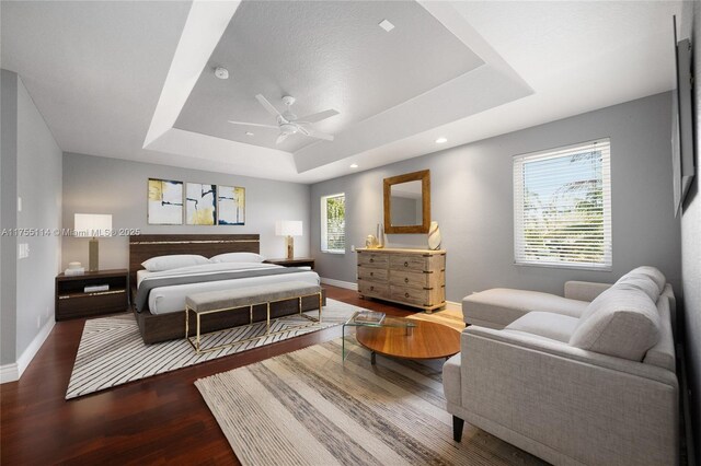 bedroom with ceiling fan, baseboards, wood finished floors, and a raised ceiling