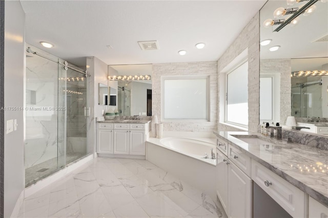 bathroom with a shower stall, a garden tub, a sink, and visible vents