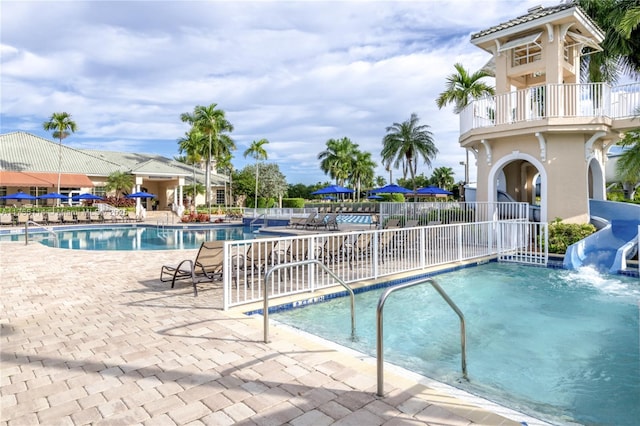 pool with fence, a patio area, and a water slide