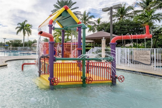 view of playground with a community pool, fence, and a water play area