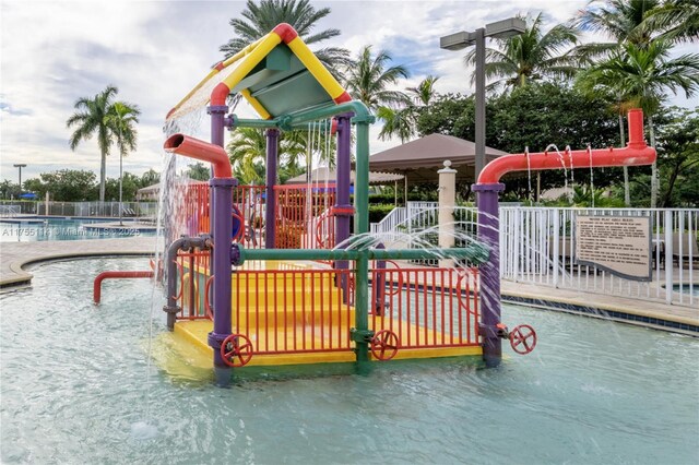 view of jungle gym featuring fence, a community pool, and a water play area