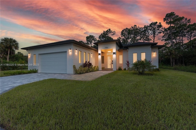 view of front of property with decorative driveway, a yard, an attached garage, and stucco siding