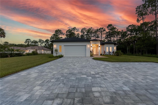 view of front facade featuring decorative driveway, an attached garage, a lawn, and stucco siding