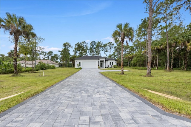 single story home with a front lawn, decorative driveway, and a garage