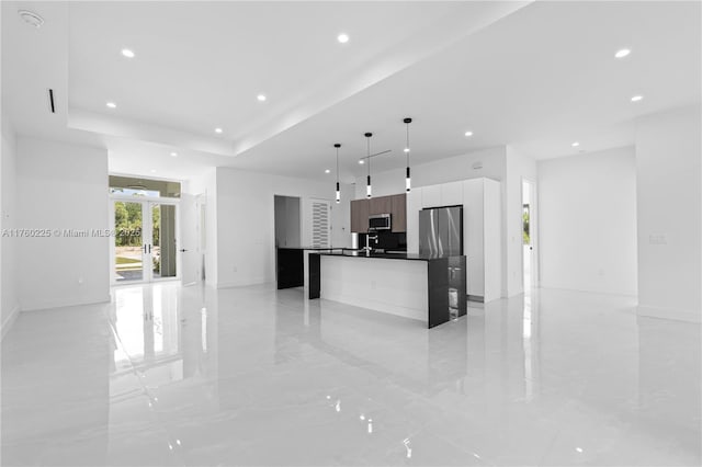 kitchen with a tray ceiling, recessed lighting, stainless steel appliances, white cabinetry, and modern cabinets