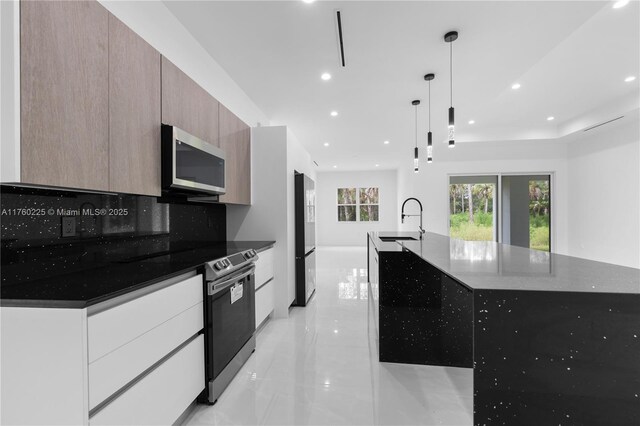 kitchen featuring modern cabinets, a sink, tasteful backsplash, a spacious island, and stainless steel appliances