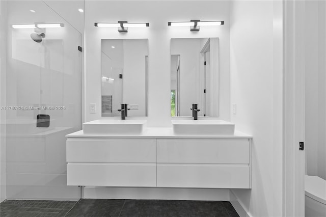 bathroom featuring double vanity, a walk in shower, toilet, and a sink