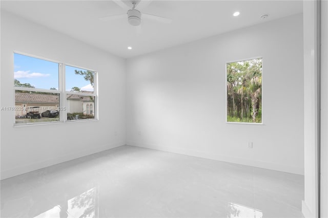 empty room with a wealth of natural light, recessed lighting, and baseboards