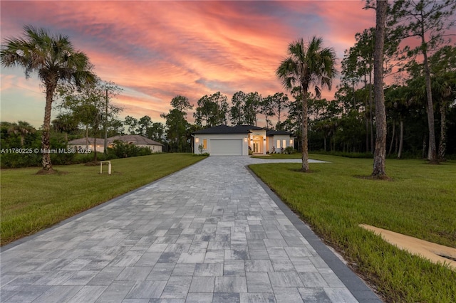 view of front facade with decorative driveway, a front lawn, and an attached garage