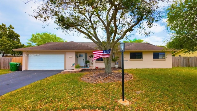 ranch-style home featuring aphalt driveway, fence, a garage, and a front lawn