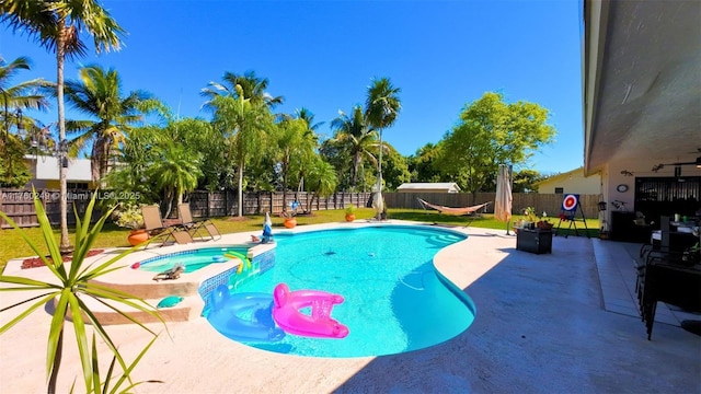 view of swimming pool featuring a yard, a patio, a pool with connected hot tub, and a fenced backyard