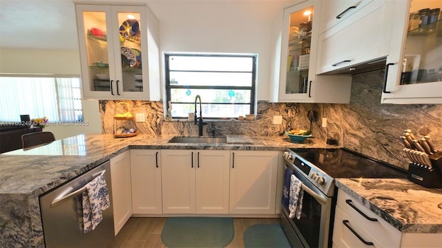 kitchen featuring a sink, plenty of natural light, backsplash, appliances with stainless steel finishes, and white cabinets