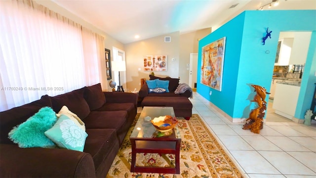 living area featuring tile patterned floors, visible vents, baseboards, and vaulted ceiling