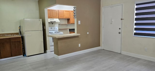 kitchen with light wood finished floors, range hood, white appliances, and baseboards