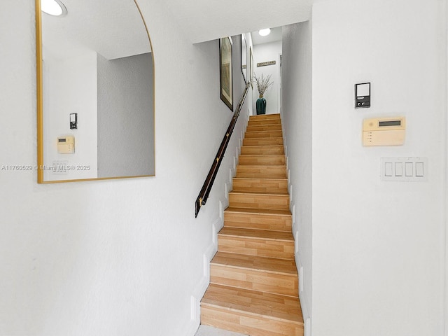 staircase featuring arched walkways and wood finished floors