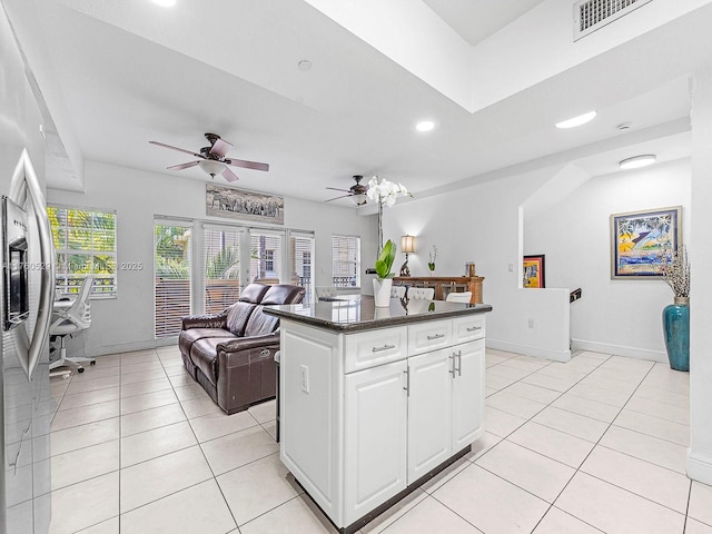 kitchen with visible vents, a kitchen island, open floor plan, white cabinetry, and light tile patterned floors