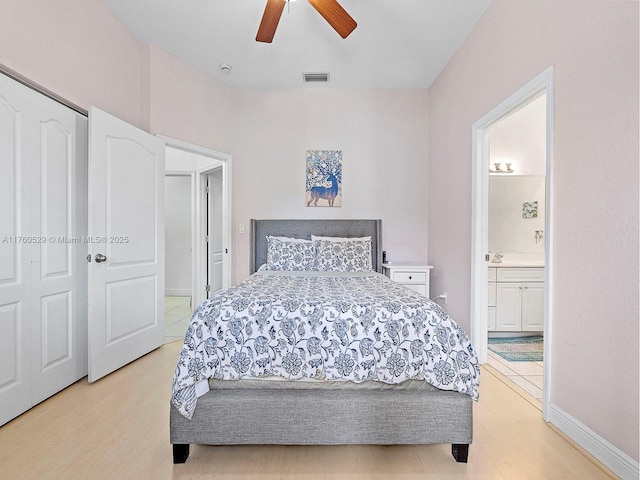 bedroom with a ceiling fan, visible vents, baseboards, ensuite bath, and light wood-style flooring