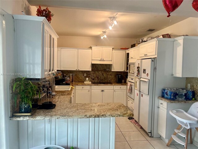 329 Minola Dr, Miami Springs, FL 33166 - kitchen featuring light tile patterned flooring, decorative backsplash, white appliances, and a peninsula