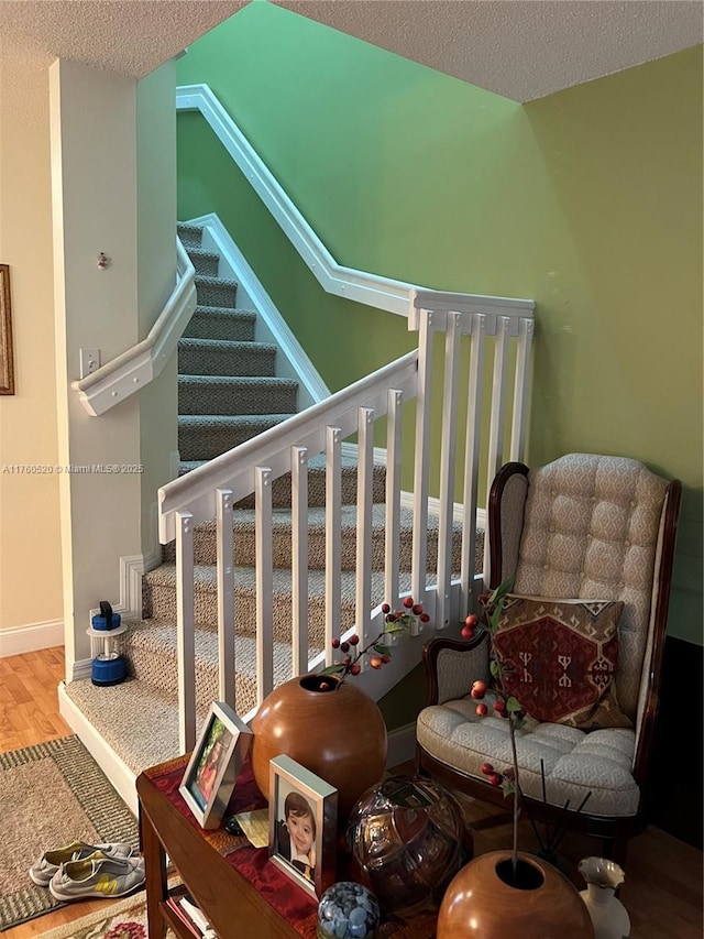 stairway featuring wood finished floors, baseboards, and a textured ceiling