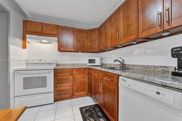 kitchen featuring white appliances, light tile patterned floors, a sink, decorative backsplash, and under cabinet range hood