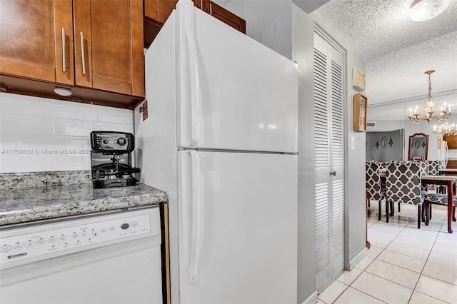 kitchen featuring white appliances, brown cabinetry, light tile patterned flooring, decorative backsplash, and a textured ceiling