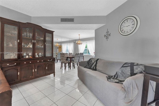 living area with visible vents, a textured ceiling, an inviting chandelier, and light tile patterned flooring