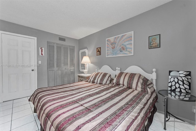 bedroom featuring light tile patterned floors, a closet, a textured ceiling, and visible vents