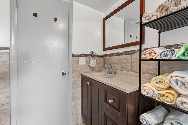 bathroom with a wainscoted wall, tile walls, and vanity