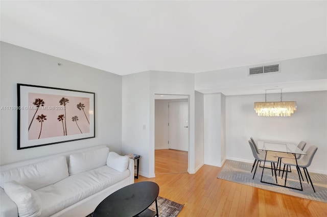 living room with a notable chandelier, visible vents, light wood-style flooring, and baseboards