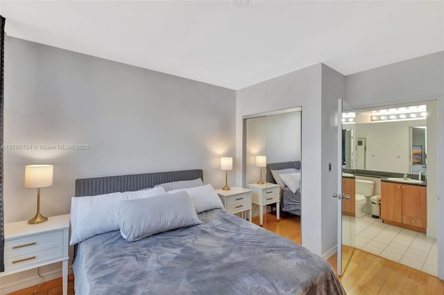 bedroom with connected bathroom, light wood-style floors, a closet, and a sink