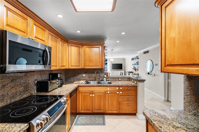 kitchen featuring decorative backsplash, brown cabinets, appliances with stainless steel finishes, and a sink