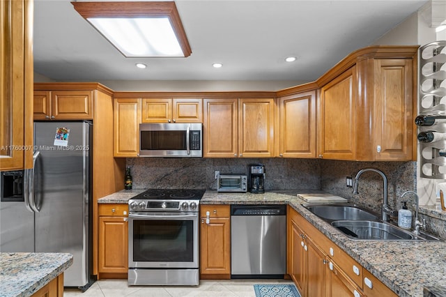 kitchen featuring brown cabinets, stainless steel appliances, and a sink