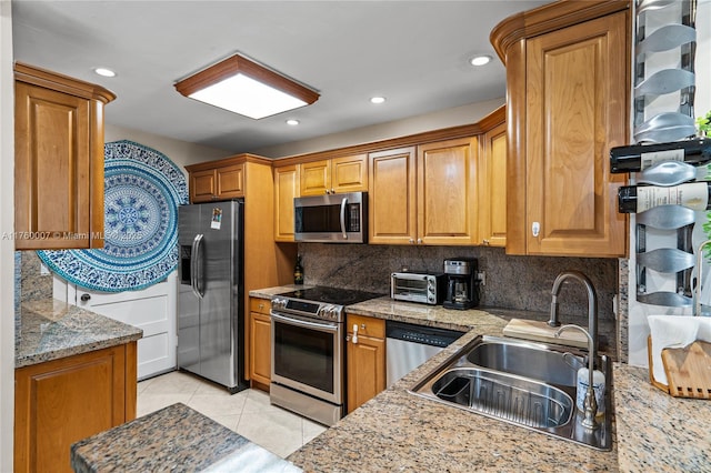 kitchen featuring a sink, brown cabinetry, backsplash, and stainless steel appliances