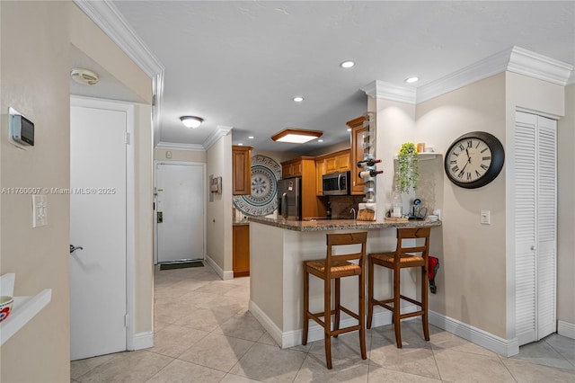 kitchen with brown cabinetry, appliances with stainless steel finishes, a peninsula, and ornamental molding