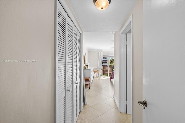 hall with light tile patterned flooring and ornamental molding